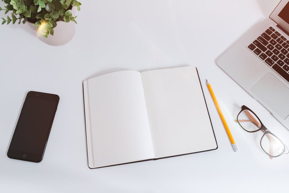 Open White Notebook Near Pencil and Eyeglasses Beside Laptop Computer on White Surface